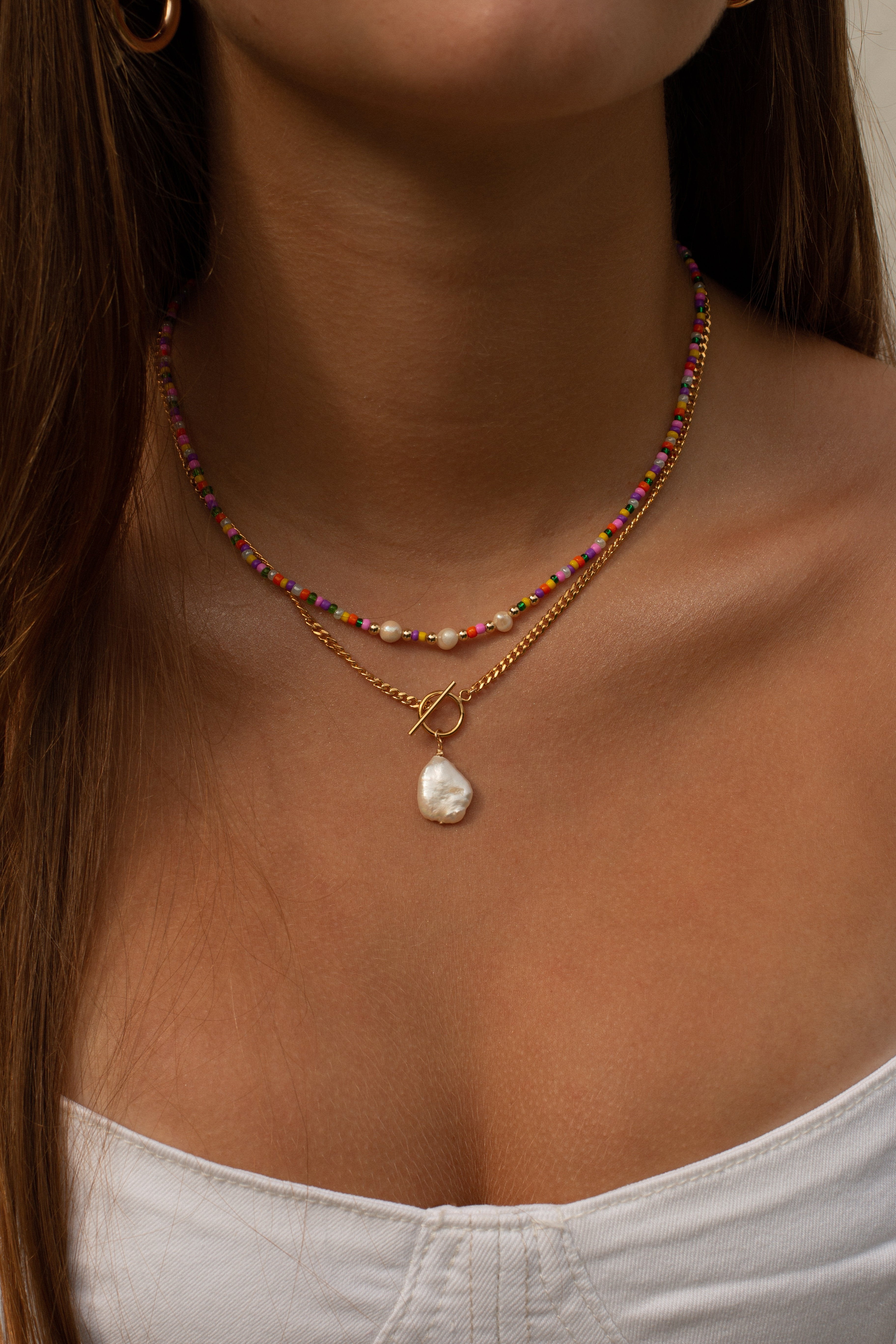 model wearing dainty and colorful pearl necklaces