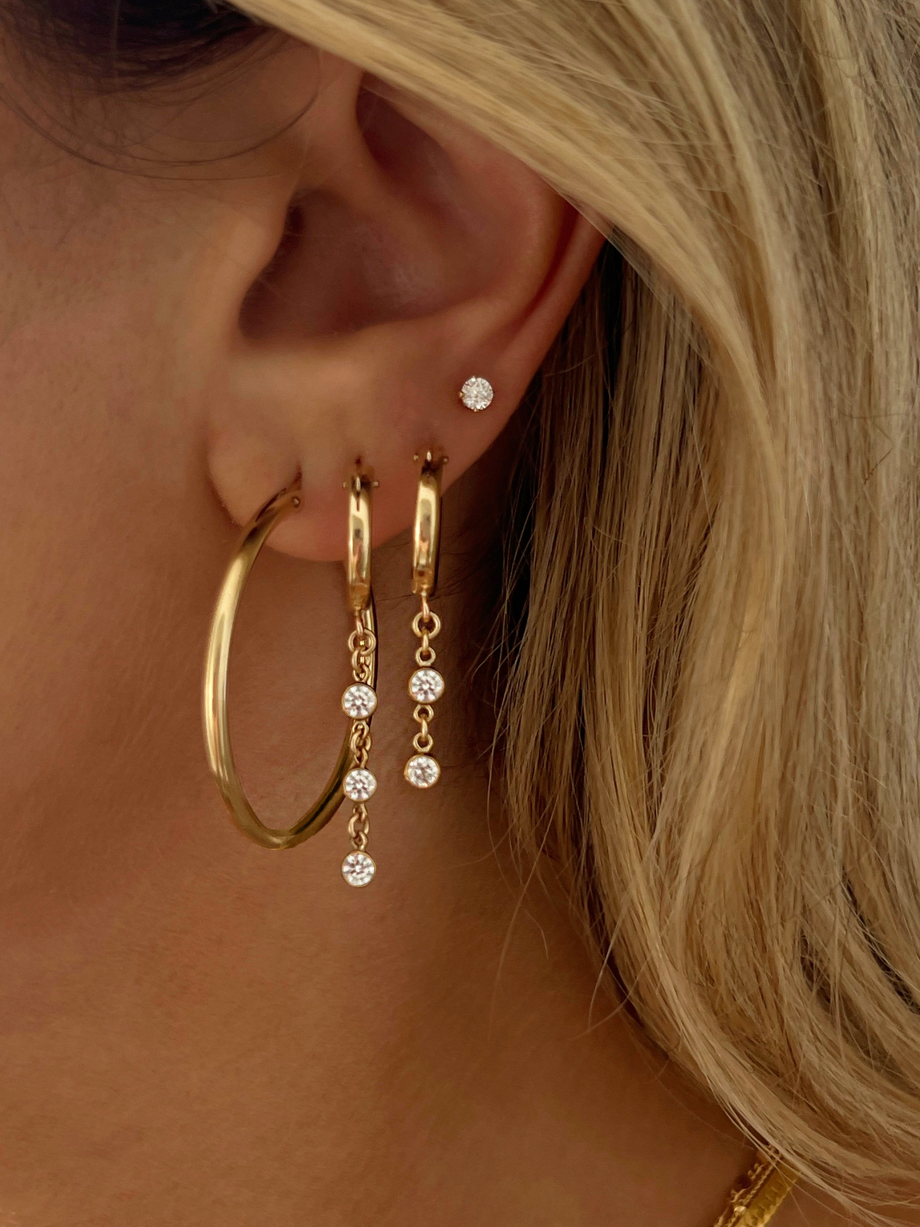 model wearing drop and dangle gold earrings with cubic zirconia diamonds